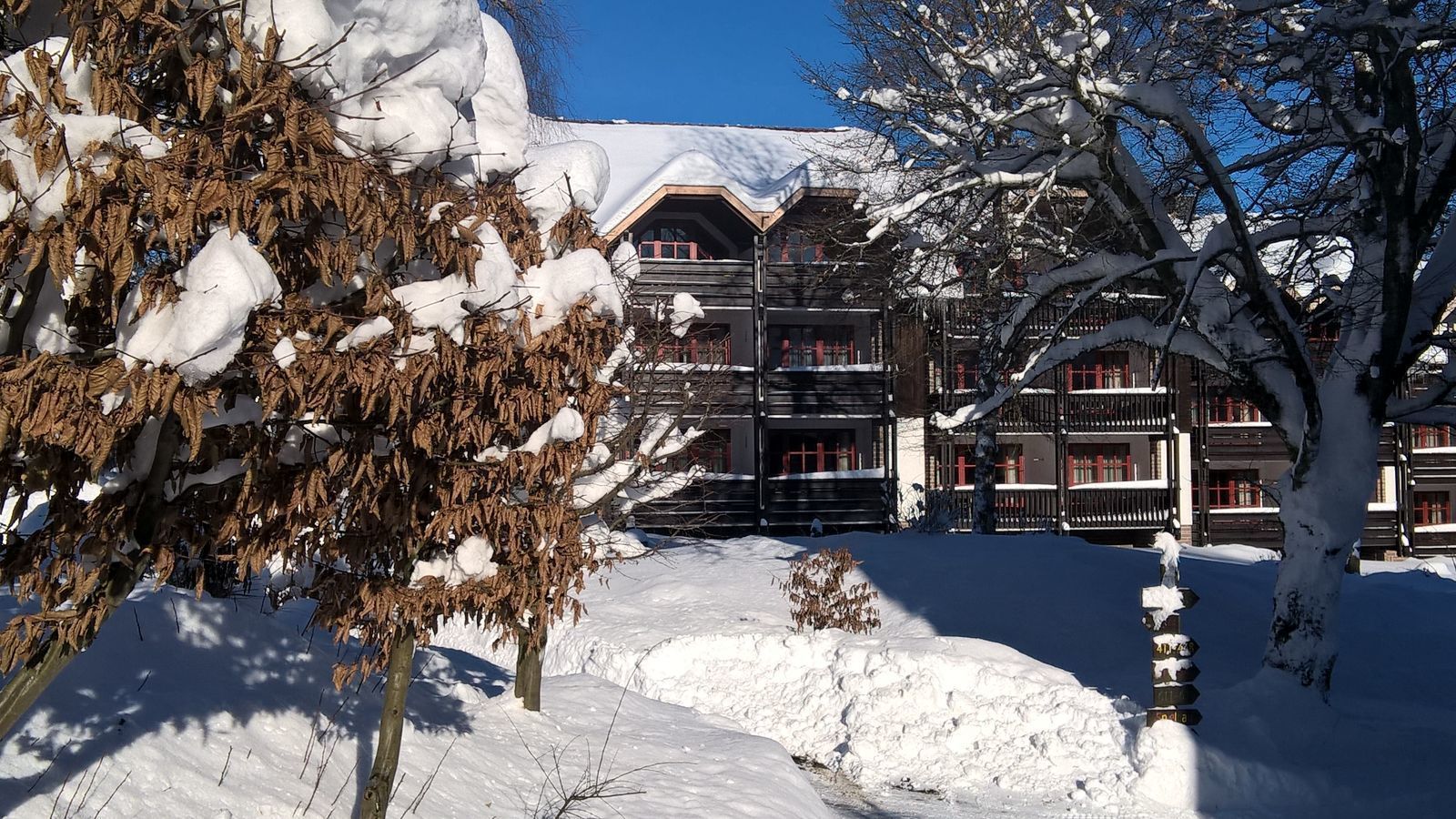 A snow-covered building with multiple balconies and a wooden facade.