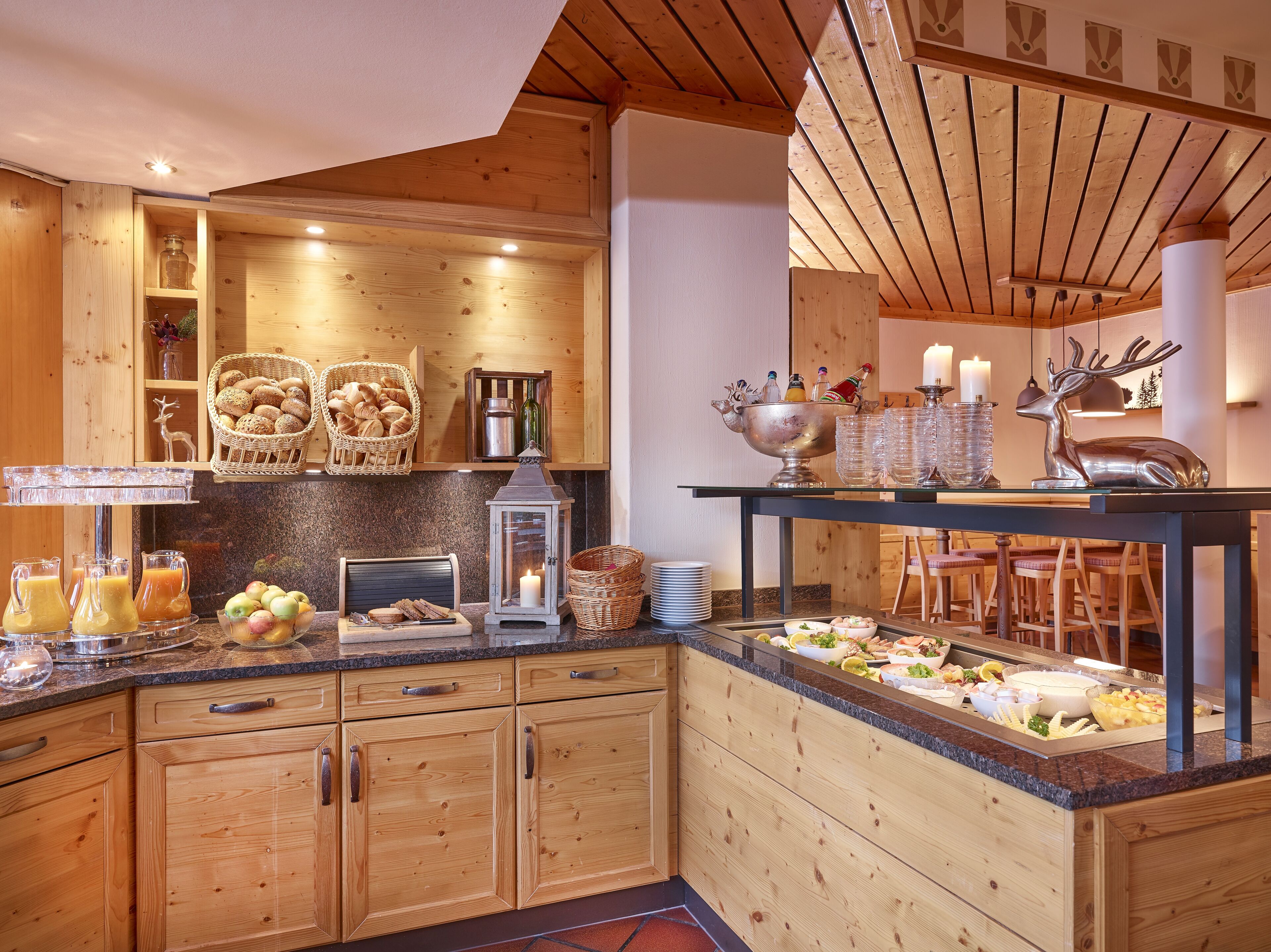 A wooden kitchen with a buffet setup, including a variety of food items and a decorative deer statue.