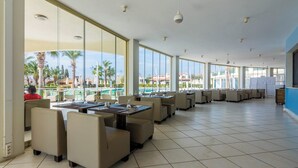 A spacious indoor area with large windows, a pool view, and multiple seating arrangements. - Apollonium Bozbuk (Milas)