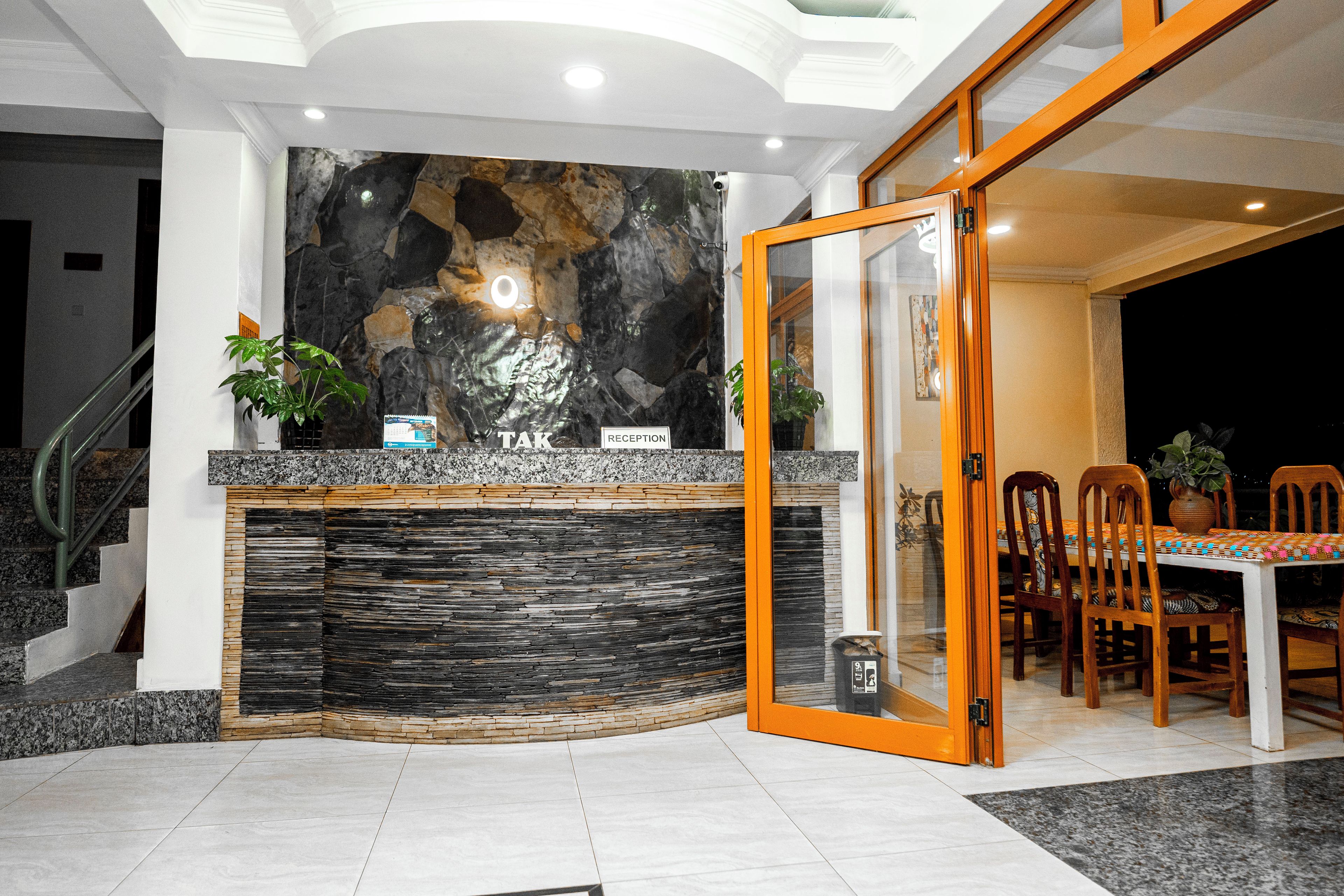 A reception area with a stone wall, a reception desk, and a dining area with chairs and a table.