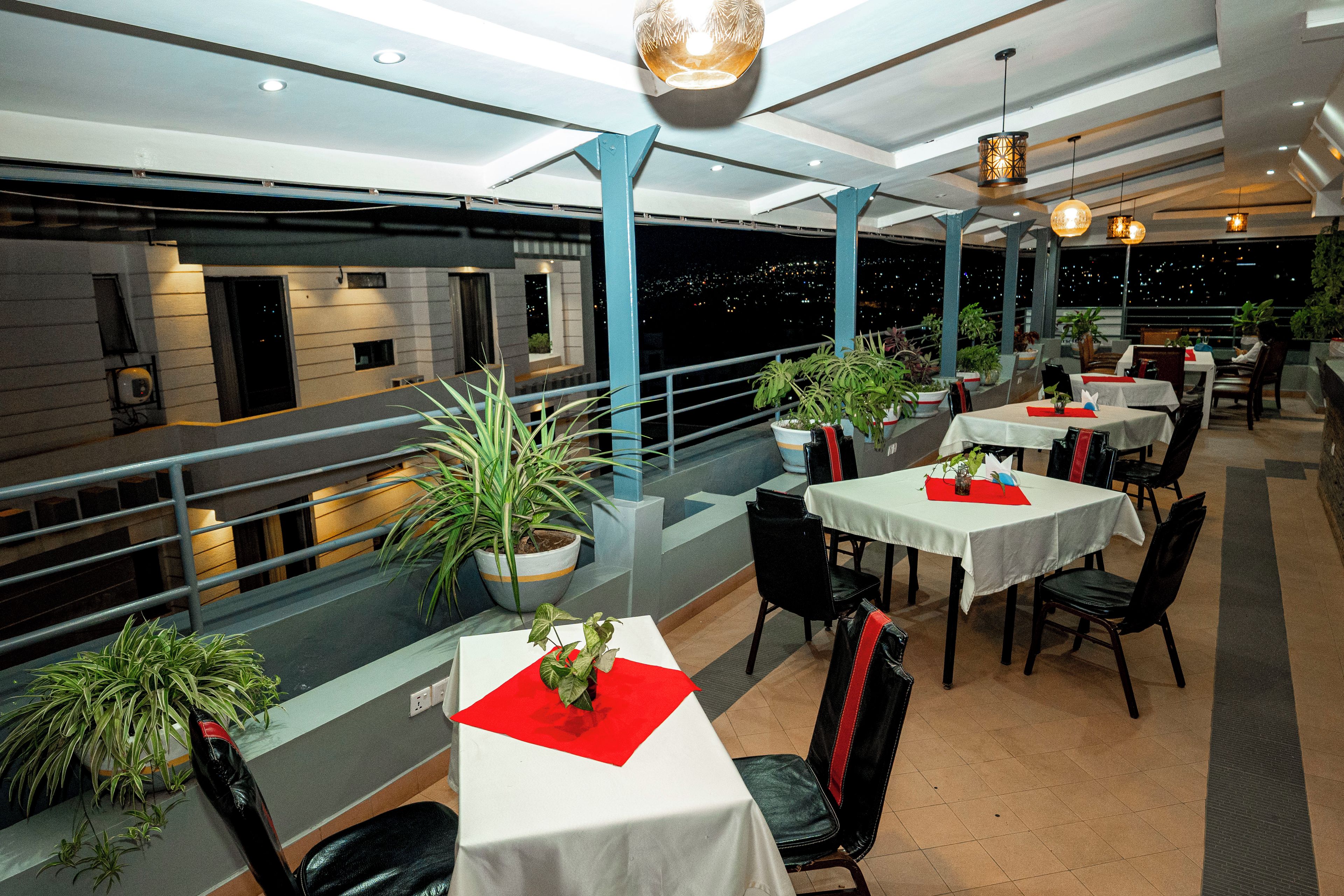 Un restaurant avec de nombreuses tables, des chaises et des plantes en pot.
