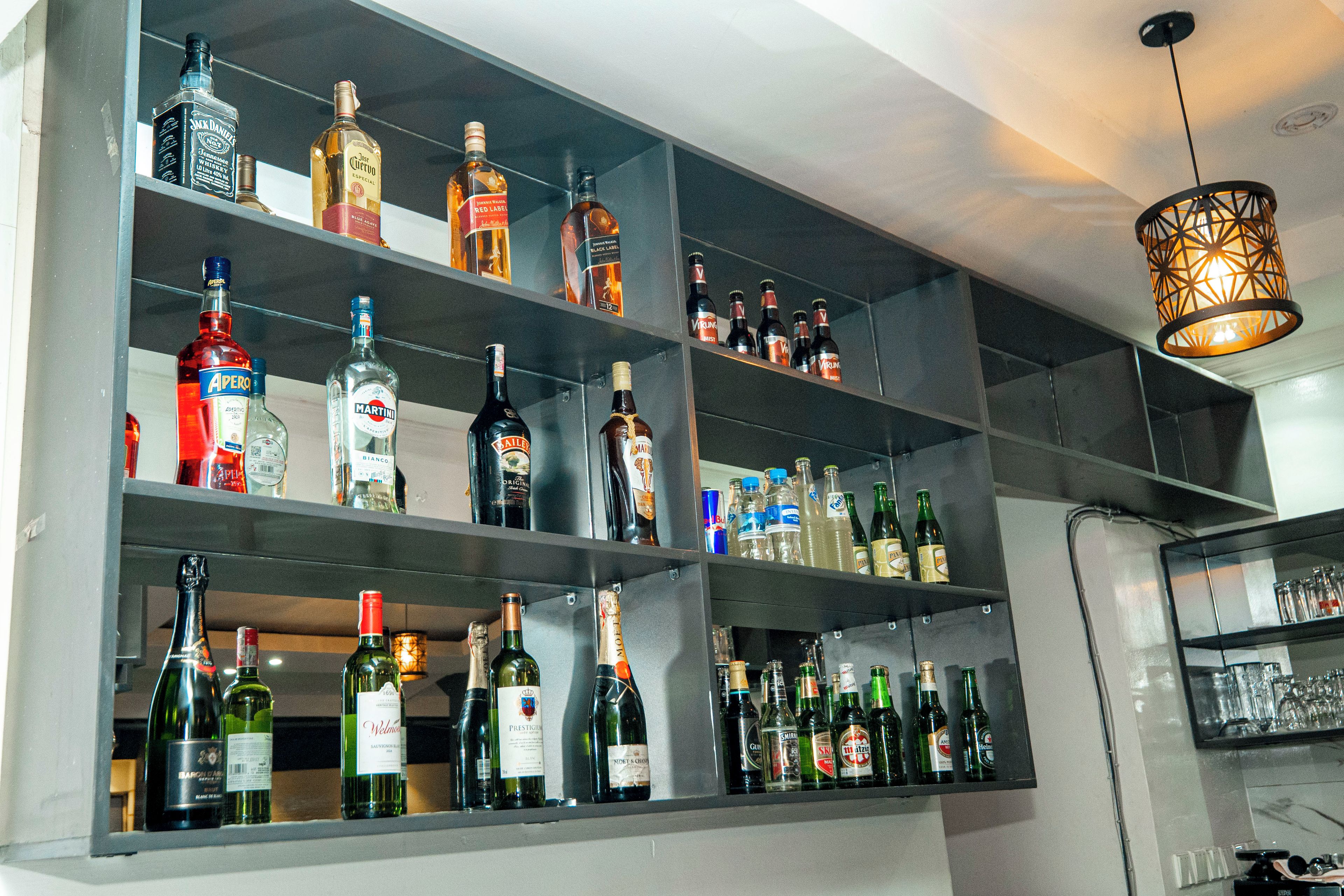 Un espace bar doté de plusieurs étagères remplies de différentes bouteilles d’alcool.