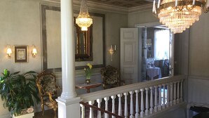 A grand foyer with a staircase, chandeliers, and ornate furniture. - Hellefors Herrgård (Hallefors)