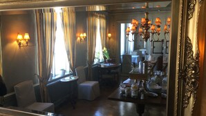 A dining area with a table set for two, a chair, a small table with a plant, and a chandelier. - Hellefors Herrgård (Hallefors)