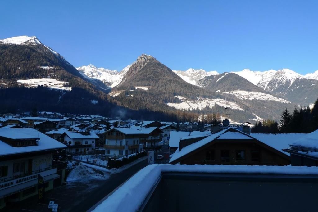 Eine Bergstadt mit schneebedeckten Gebäuden und freiem Blick auf verschneite Berge.
