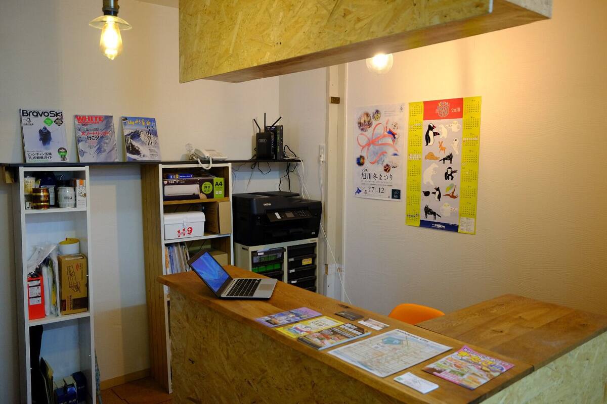 A reception desk with a laptop, shelves with various items, and wall decorations including a calendar and posters.