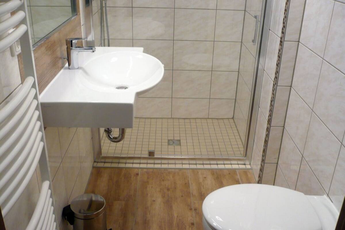 A small, modern bathroom with a white sink, toilet, and shower.