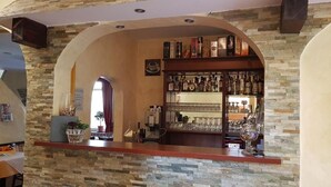 Una zona de bar con pared de piedra, estantes llenos de botellas y una máquina de café.