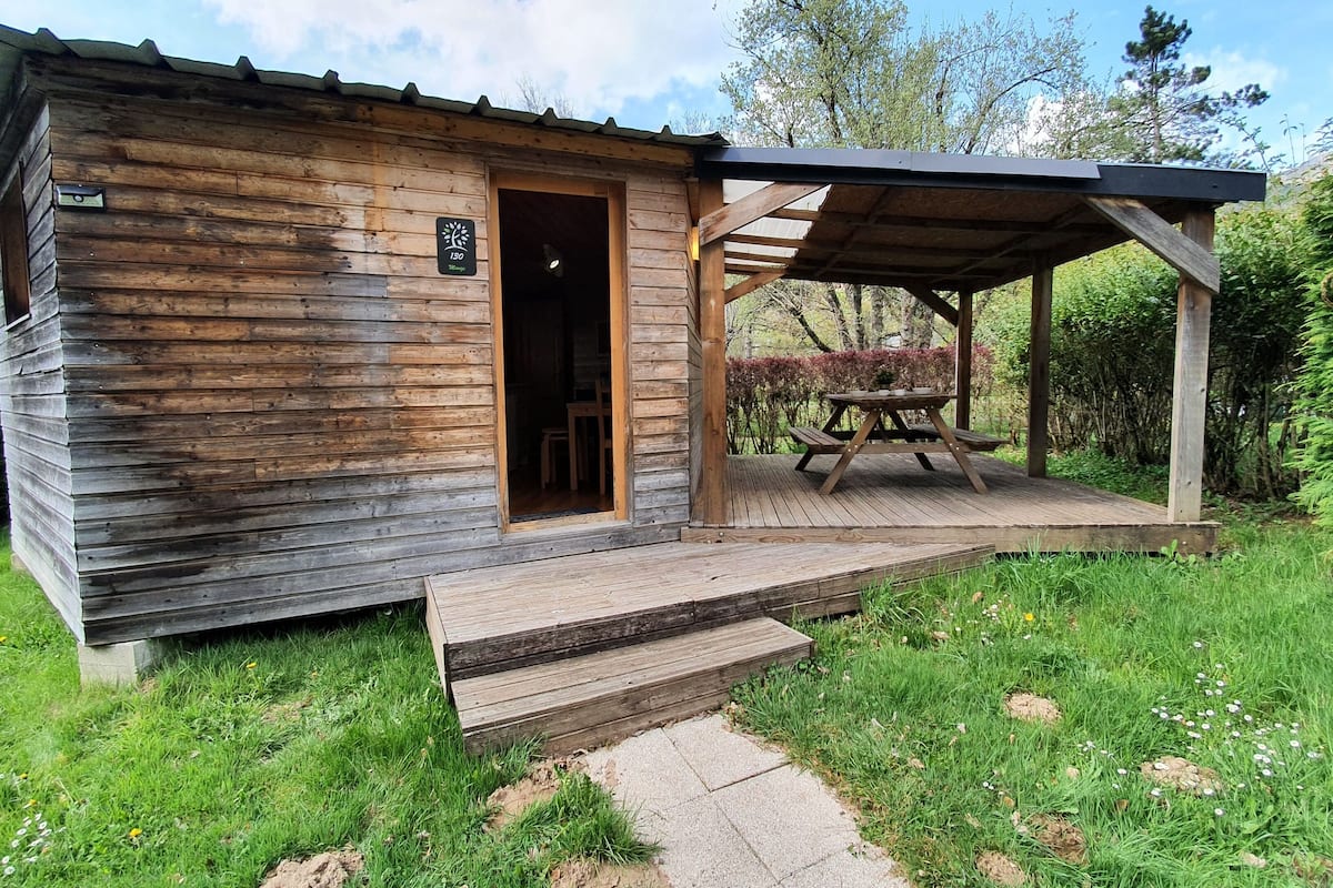 Una cabaña rústica de madera con un porche cubierto y una mesa de picnic.