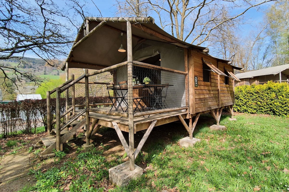 Una cabaña de madera rústica con balcón, rodeada por un paisaje natural.