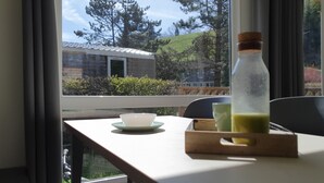 A room with a table by a window, a bottle of drink, and a bowl. - Camping les Vernières (La Bourboule)