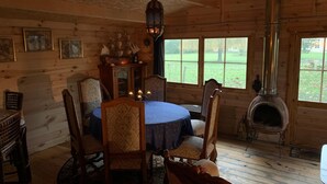 A cozy cabin interior with a round table, wooden chairs, a ship model, and a wood stove. - Château de Grand Tonne (Thue et Mue)
