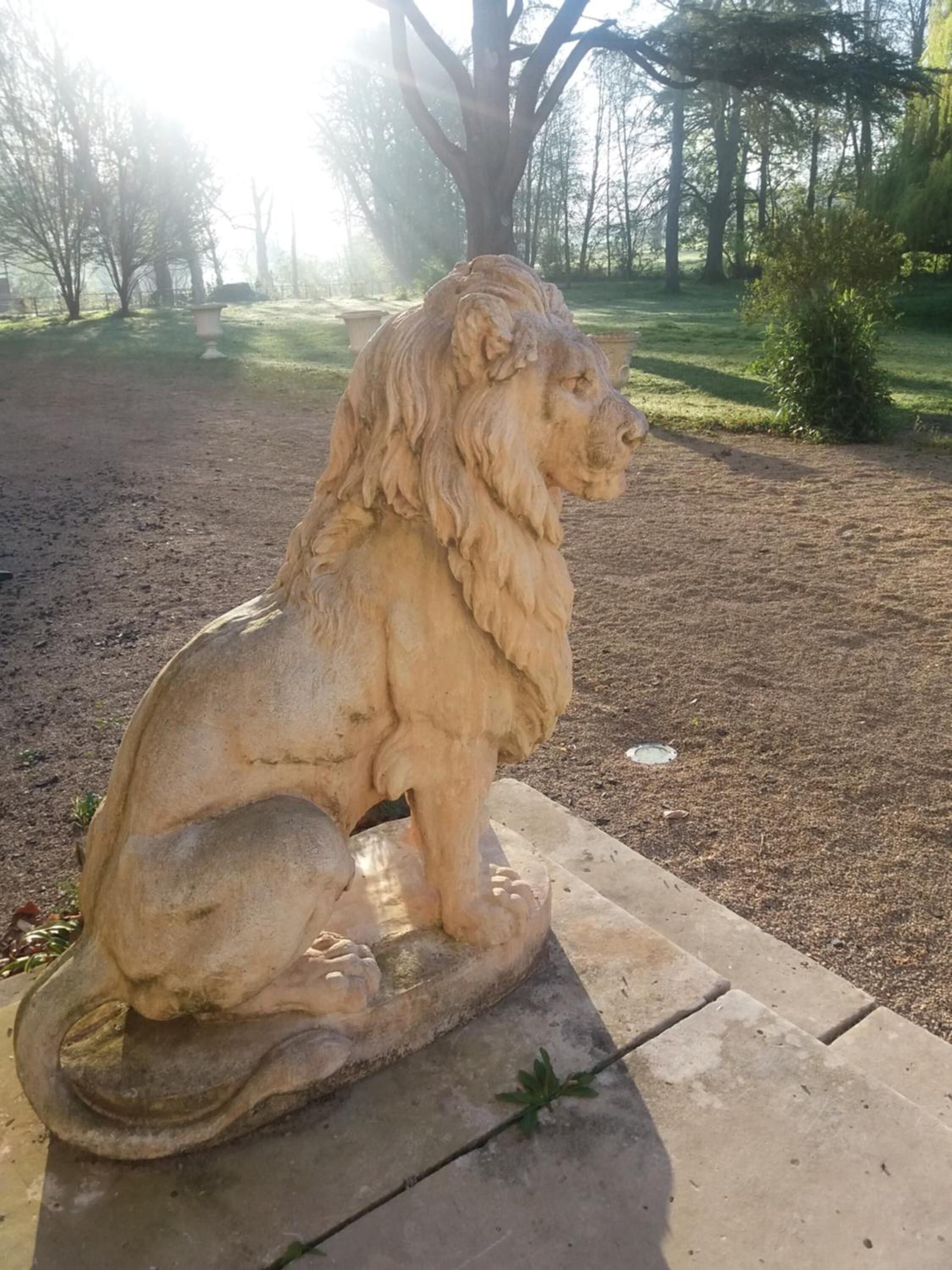Une statue de lion en pierre, dans un parc.