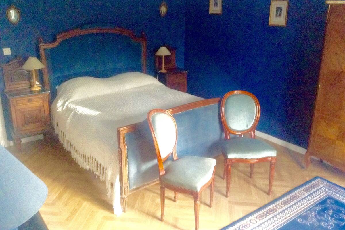 A bedroom with a large bed, two chairs, a nightstand, and a dresser.