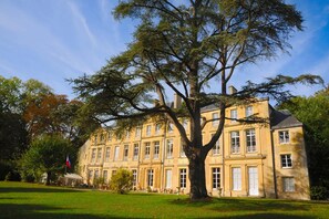 A large, historic building with a symmetrical facade, multiple windows, and a prominent tree in front. - Château de Grand Tonne (Thue et Mue)