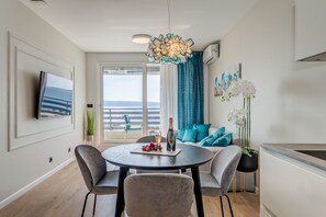 A modern dining area with a round table, two chairs, a bottle of wine, and a plate of fruit. - Beachfront Holiday Apartments (Split)