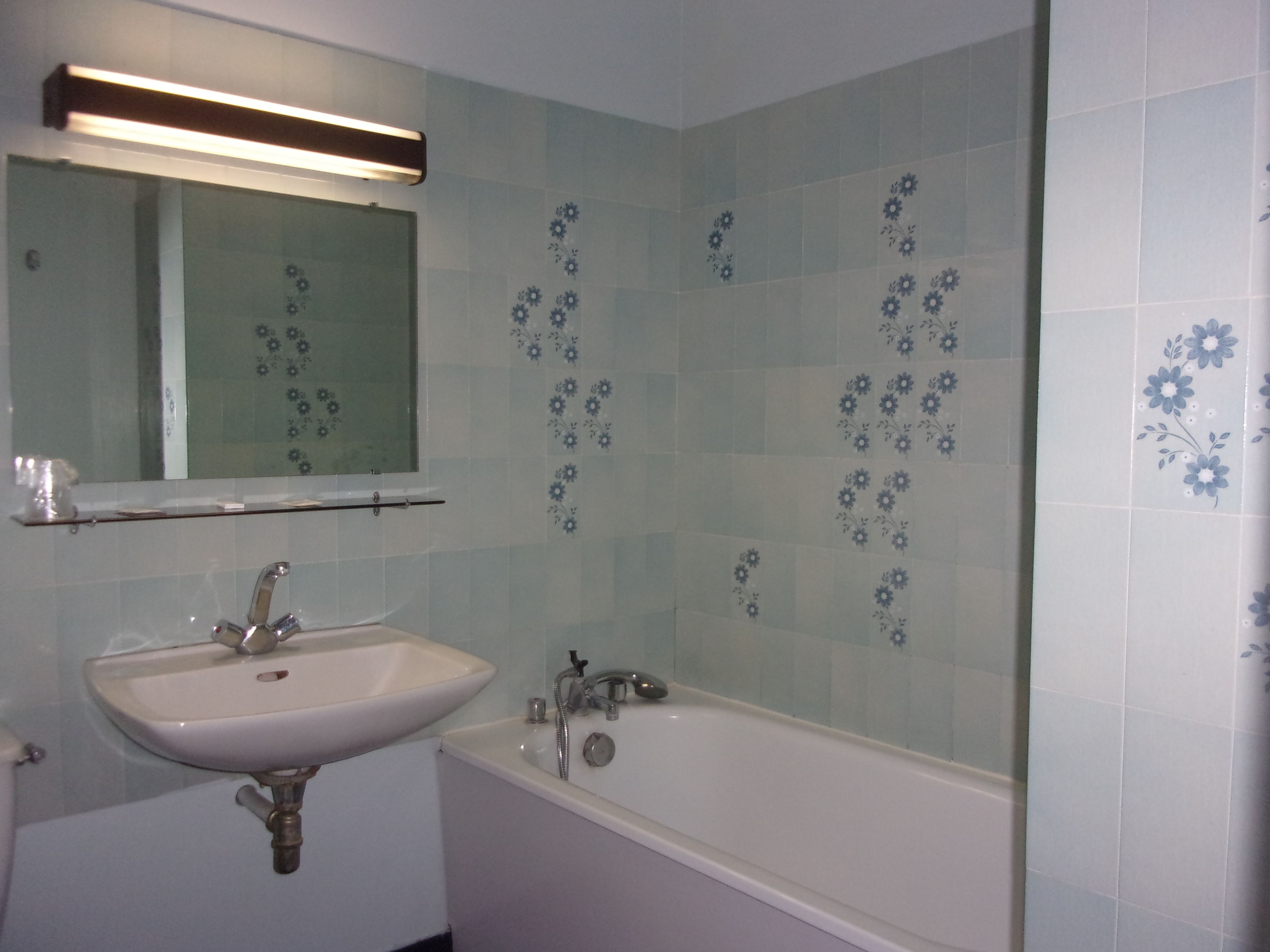 Un baño con lavamanos blanco, un espejo y una bañera.