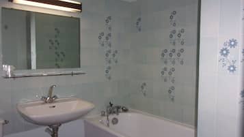 Un baño con lavamanos blanco, un espejo y una bañera.