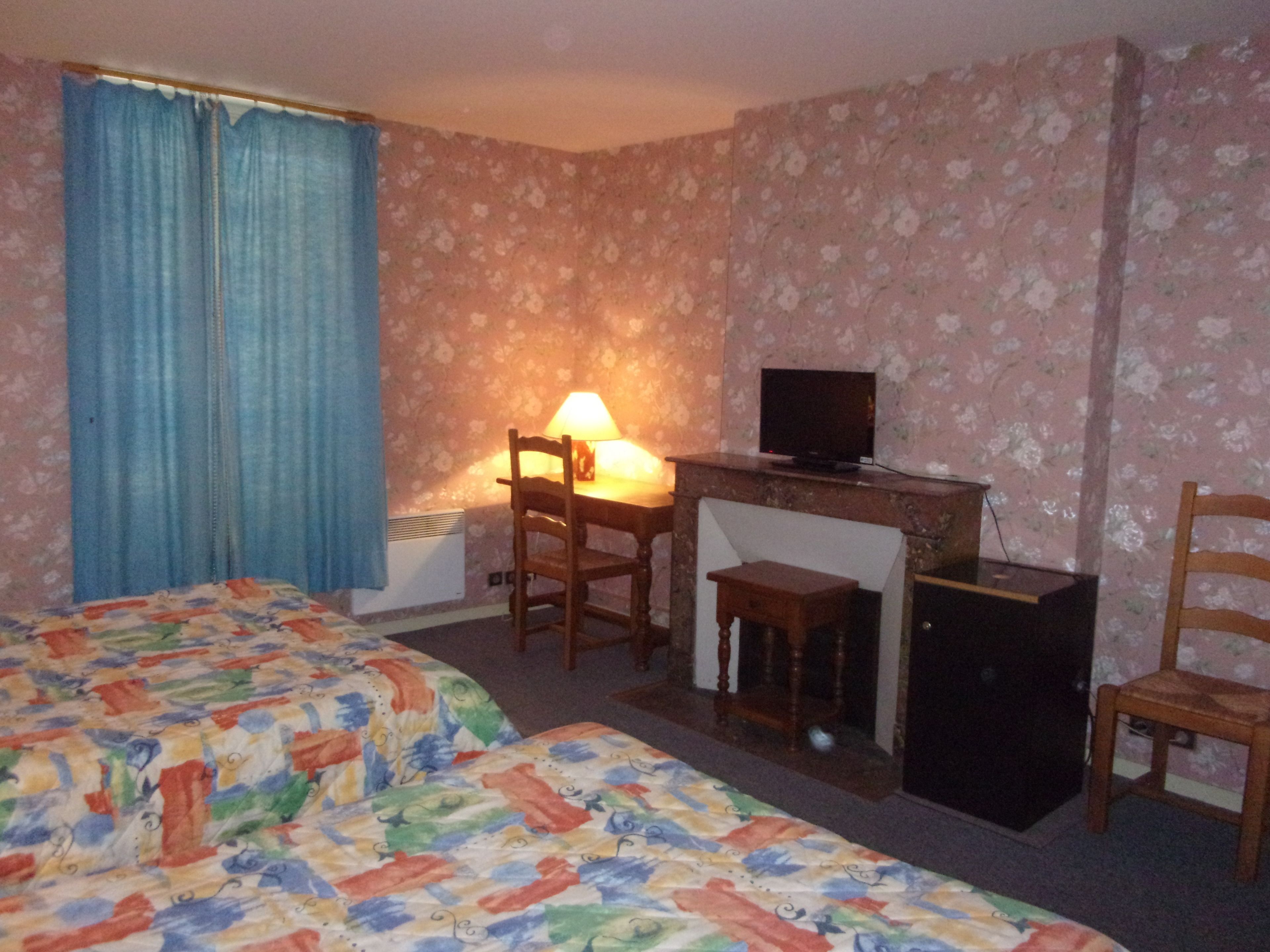 Una habitación de hotel con dos camas, un escritorio con lámpara, un televisor y un mueble bajo.