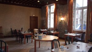 A dining area with multiple tables and chairs, stone walls, and large windows with curtains. - Jackotel Orleans (Orléans)