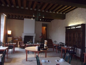 A dining area with wooden tables and chairs, a fireplace, and a staircase leading to an upper level. - Jackotel Orleans (Orléans)