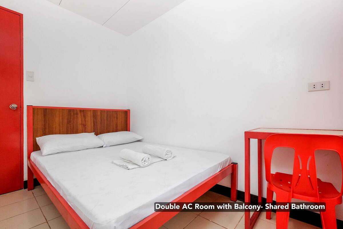 A double AC room with a balcony and a shared bathroom.