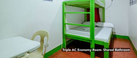 Une chambre climatisée pour trois personnes, avec salle de bain commune, un lit superposé, une petite table et une chaise.