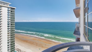 A high-rise building with a balcony overlooking a beach and ocean.
