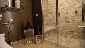 Un baño con ducha de vidrio, un espejo y dos lámparas de estilo farol en el suelo.