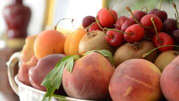 A bowl of fruits including peaches, kiwis, and cherries.