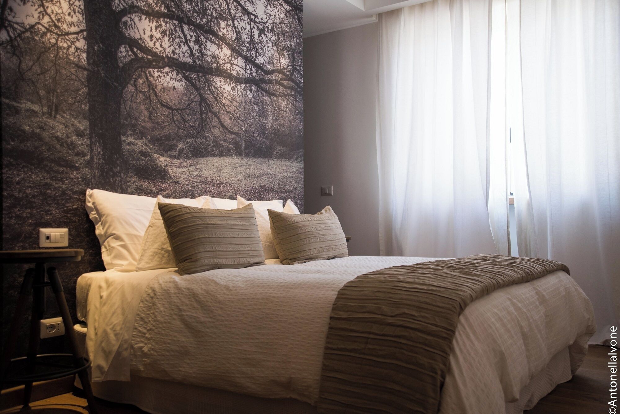 Une chambre à coucher avec un lit, des oreillers, une table de chevet et une lampe fixée au mur.