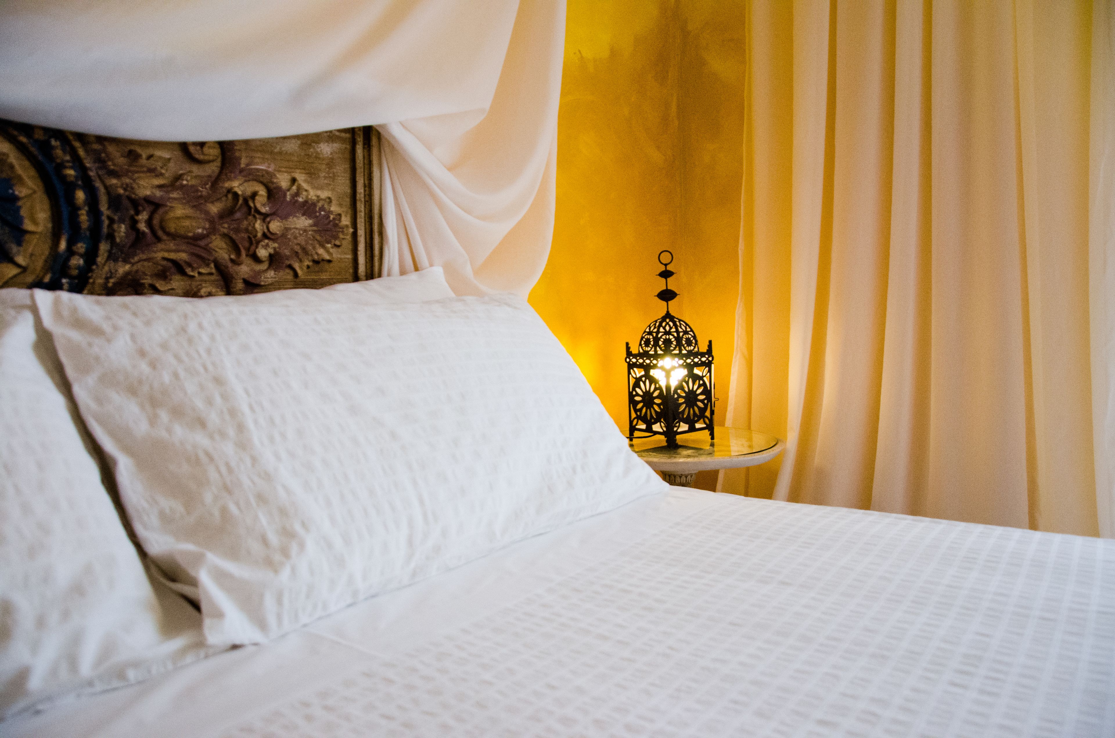 A neatly made bed with white linens and a decorative headboard.