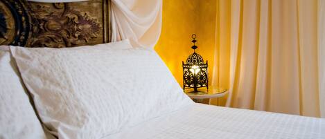 A neatly made bed with white linens and a decorative headboard.