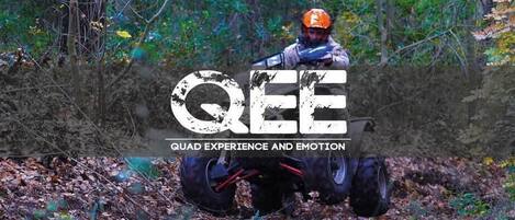 A person in an orange helmet and protective gear, possibly engaged in an outdoor activity, with a forested background.