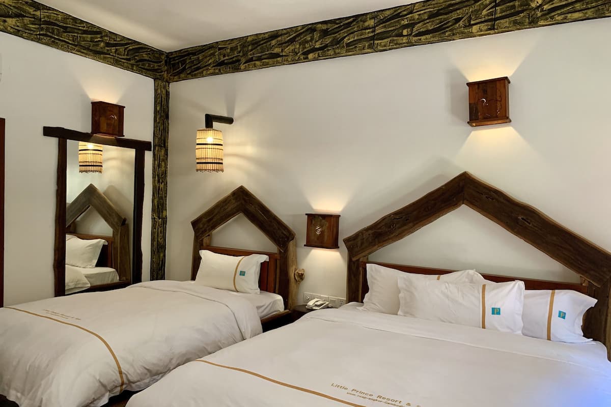 Ein Hotelzimmer mit zwei Betten, jeweils mit Holz Kopfteil, weißer Bettwäsche und einem Spiegel an der linken Wand.