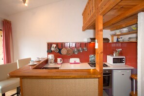 A compact kitchen with a wooden counter, a coffee maker, a toaster, and a microwave.