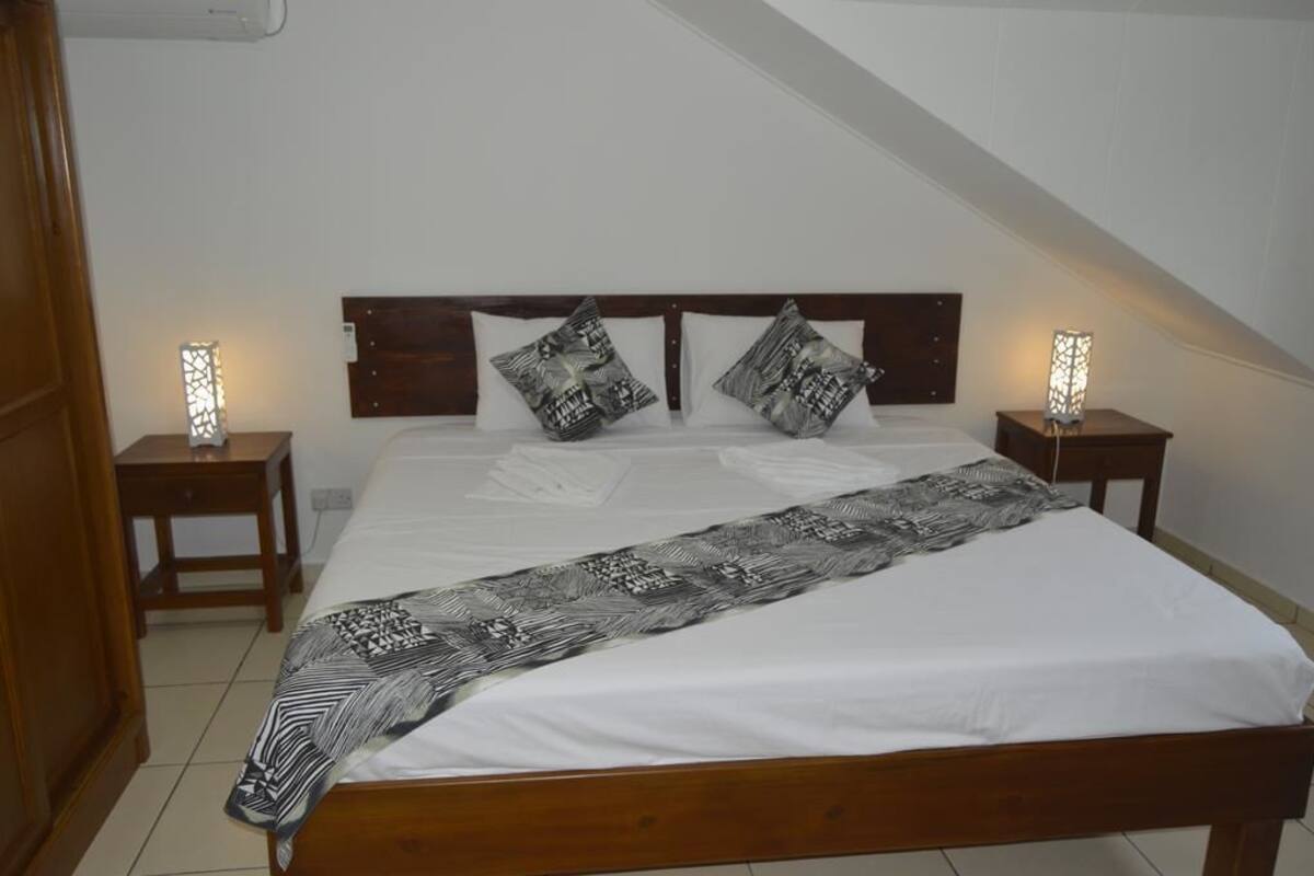 A neatly made bed with a patterned bedspread, two bedside tables with lamps, and a wooden headboard.