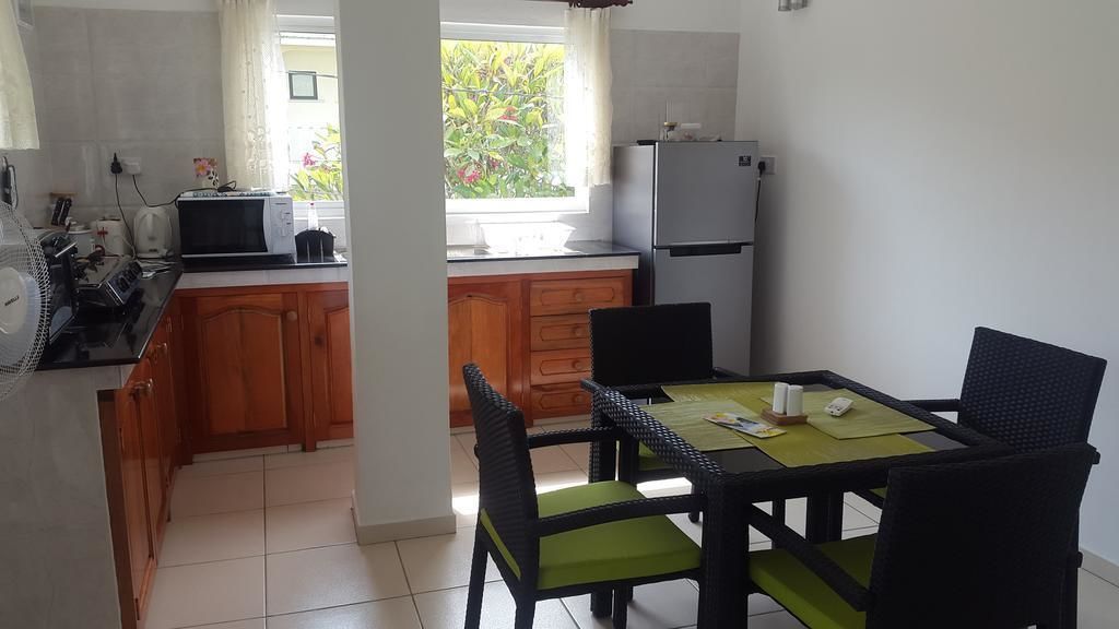 Une cuisine compacte avec des meubles en bois, une table à manger avec des chaises, un four à micro-ondes et un réfrigérateur.