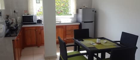 Une cuisine compacte avec des meubles en bois, une table à manger avec des chaises, un four à micro-ondes et un réfrigérateur.