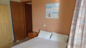 Un dormitorio con una cama grande, un armario de madera, una mesita de noche y un cuadro en la pared.
