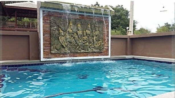 A swimming pool with a stone wall featuring a relief sculpture. - Wongsuwan Pool Villa (Hua Hin)