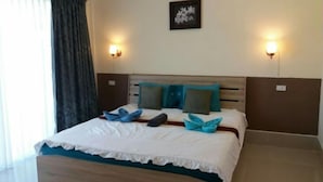 A hotel room with a wooden bed, white bedding, teal pillows, and two wall-mounted lights. - Wongsuwan Pool Villa (Hua Hin)