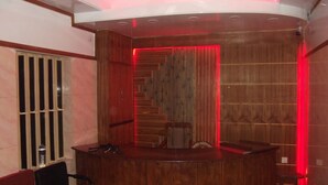 A reception area with a wooden reception desk, a chair, and a wooden wall paneling. - Azmiry Residential Hotel (Kushtia)