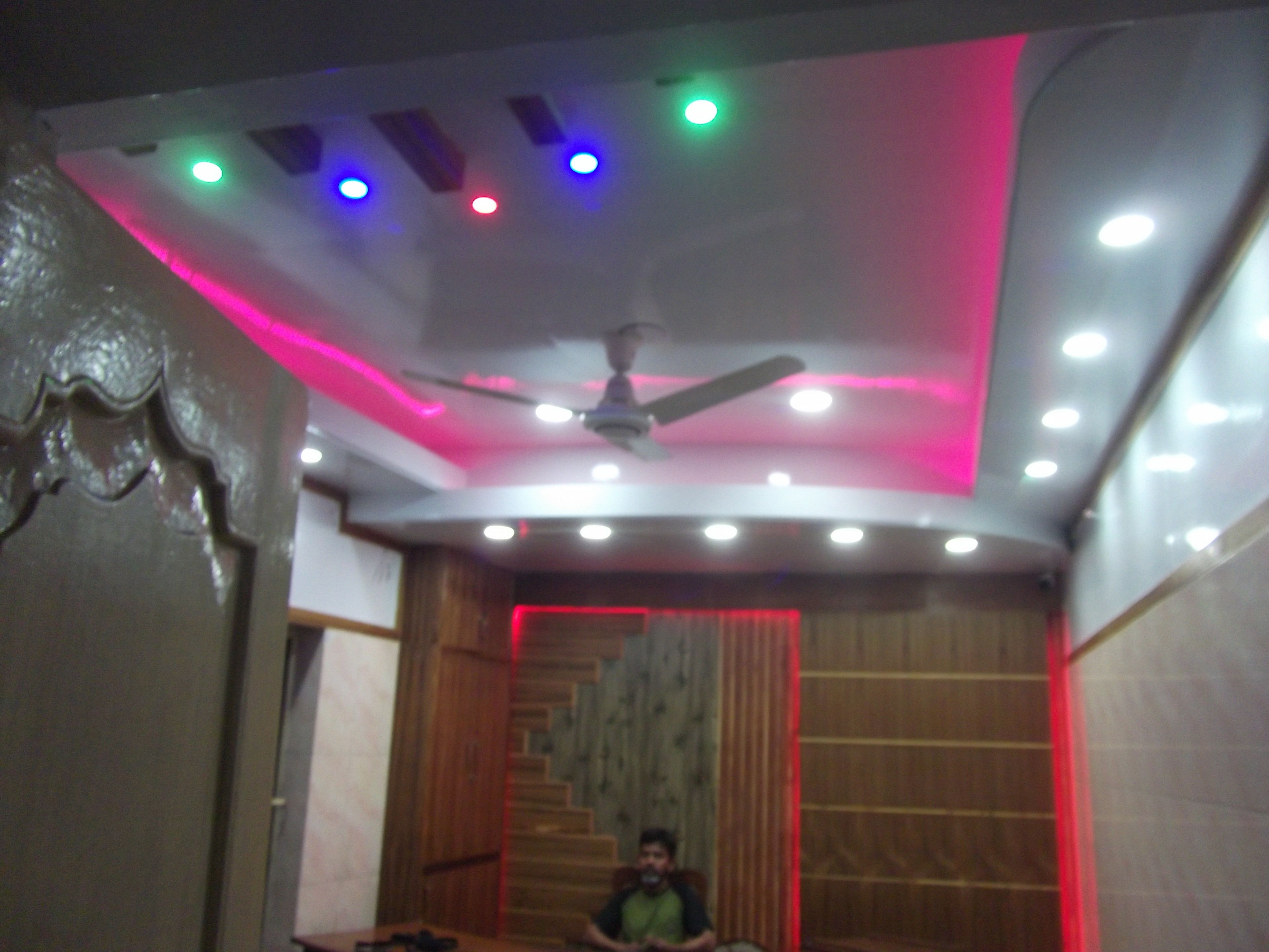 Una habitación con ventilador de techo, iluminación empotrada y una escalera de madera.
