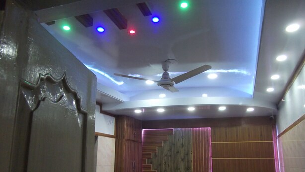 A room with a ceiling fan, recessed lighting, and a wooden staircase. - Azmiry Residential Hotel (Kushtia)