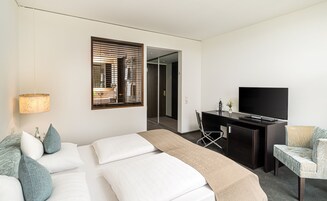 Una habitación de hotel con una cama, un escritorio, un televisor y una silla.