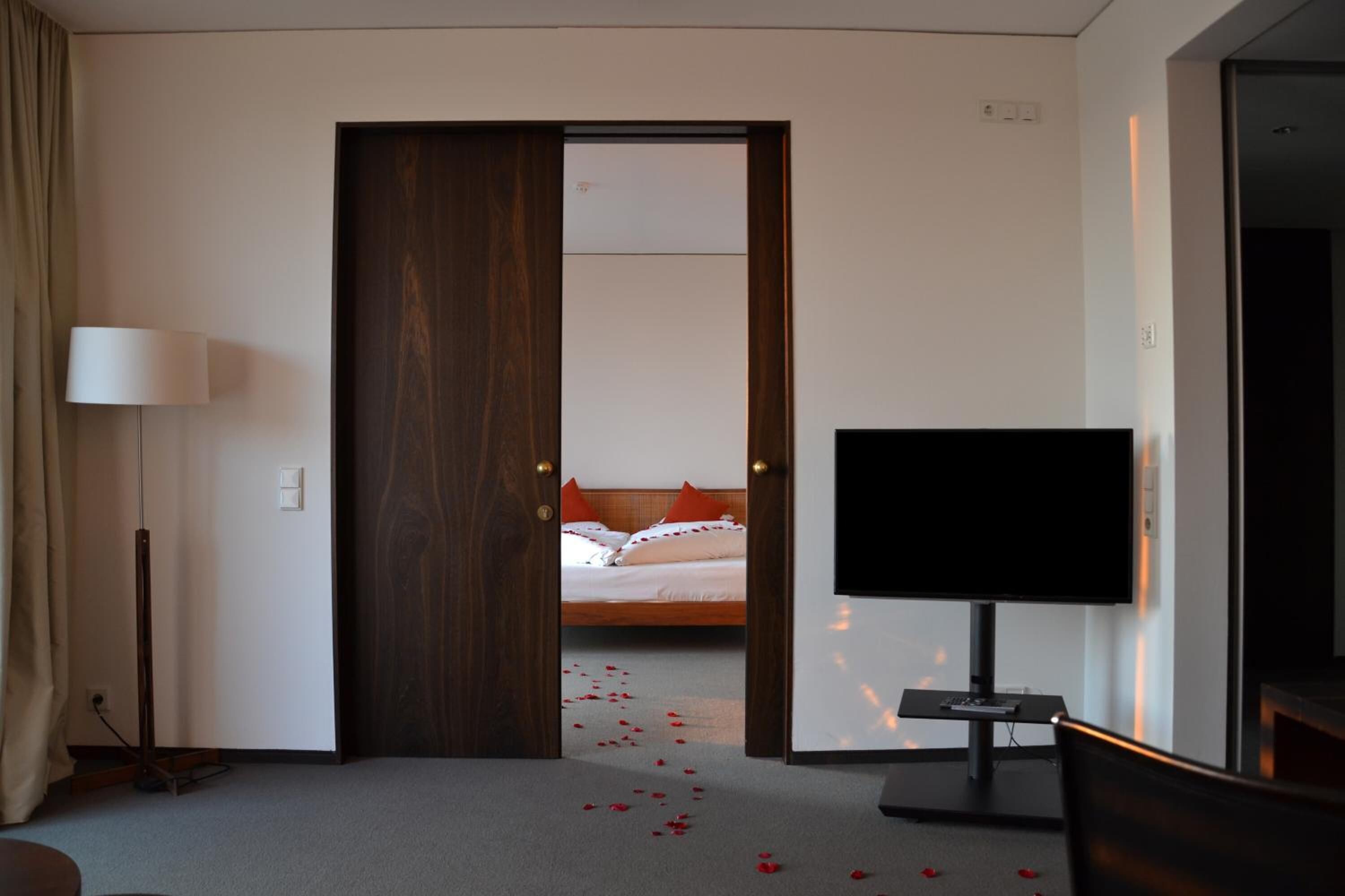 Ett hotellrum med en säng, en tv och en dörr som leder till ett annat rum.