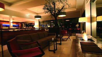 Un área de lounge moderna con asientos, un bar y un gran árbol como elemento central.