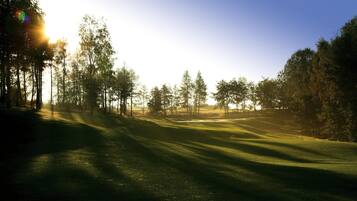 Un campo de golf con un sendero despejado, rodeado de árboles y un cielo claro.