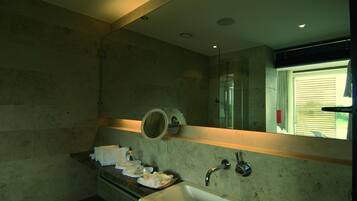 A modern bathroom with a large mirror, a bathtub, and a countertop with toiletries.